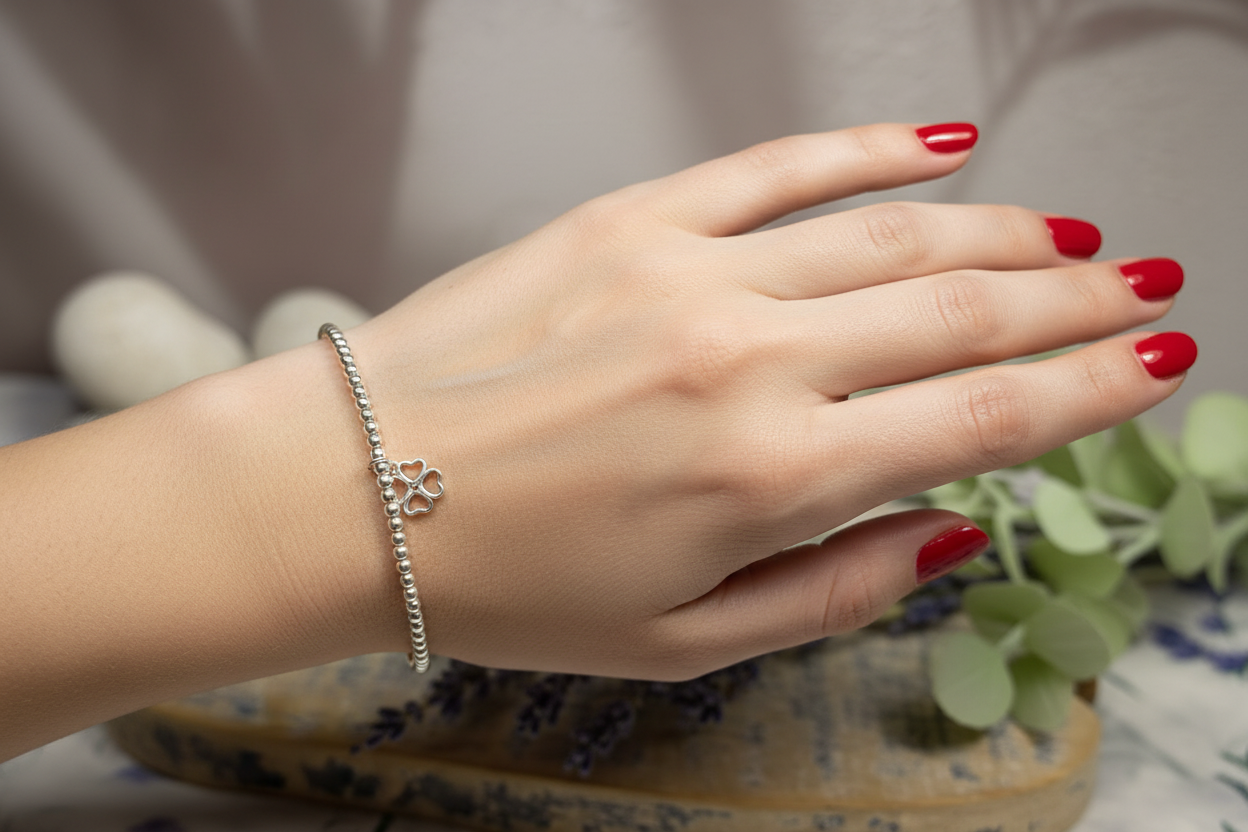 Sterling silver beaded bracelet with heart flower charm on lady's hand with red nails