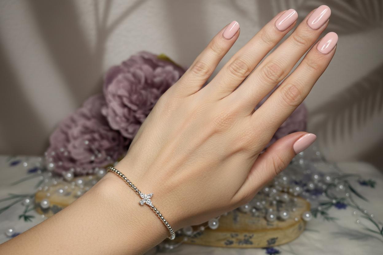Sterling silver beaded bracelet with flower charm on lady's hand with painted nails